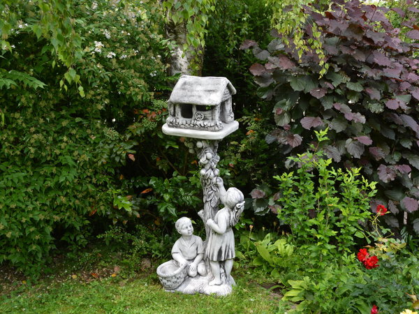 Junge und Mädchen mit einer Vogelhaus-Statue