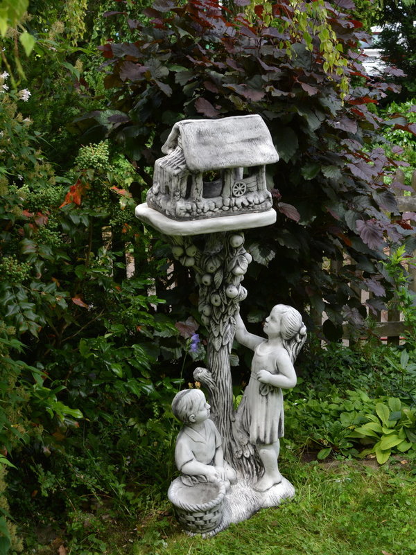 Junge und Mädchen mit einer Vogelhaus-Statue